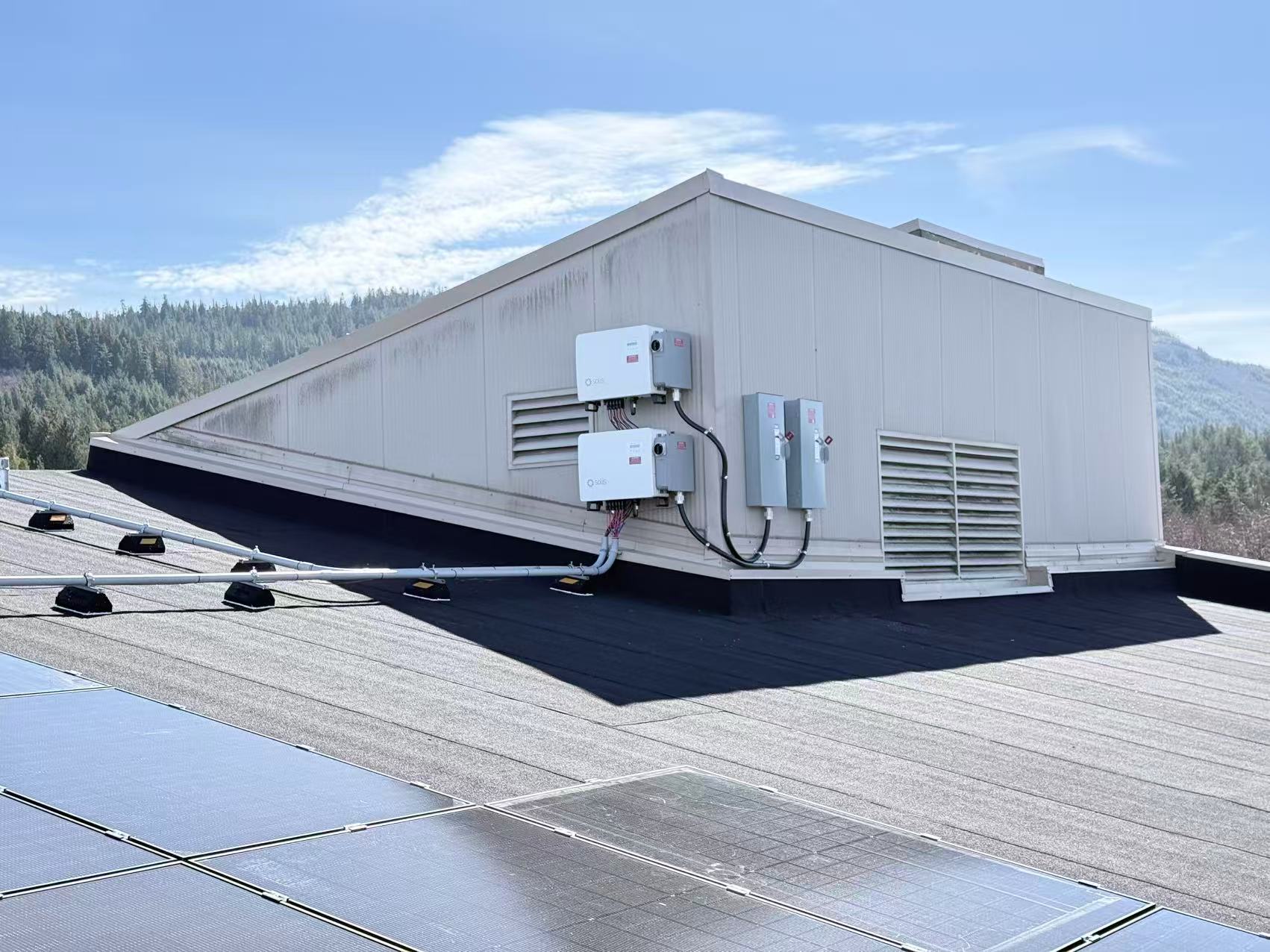 Inverters and electrical equipment beside a commercial rooftop solar installation