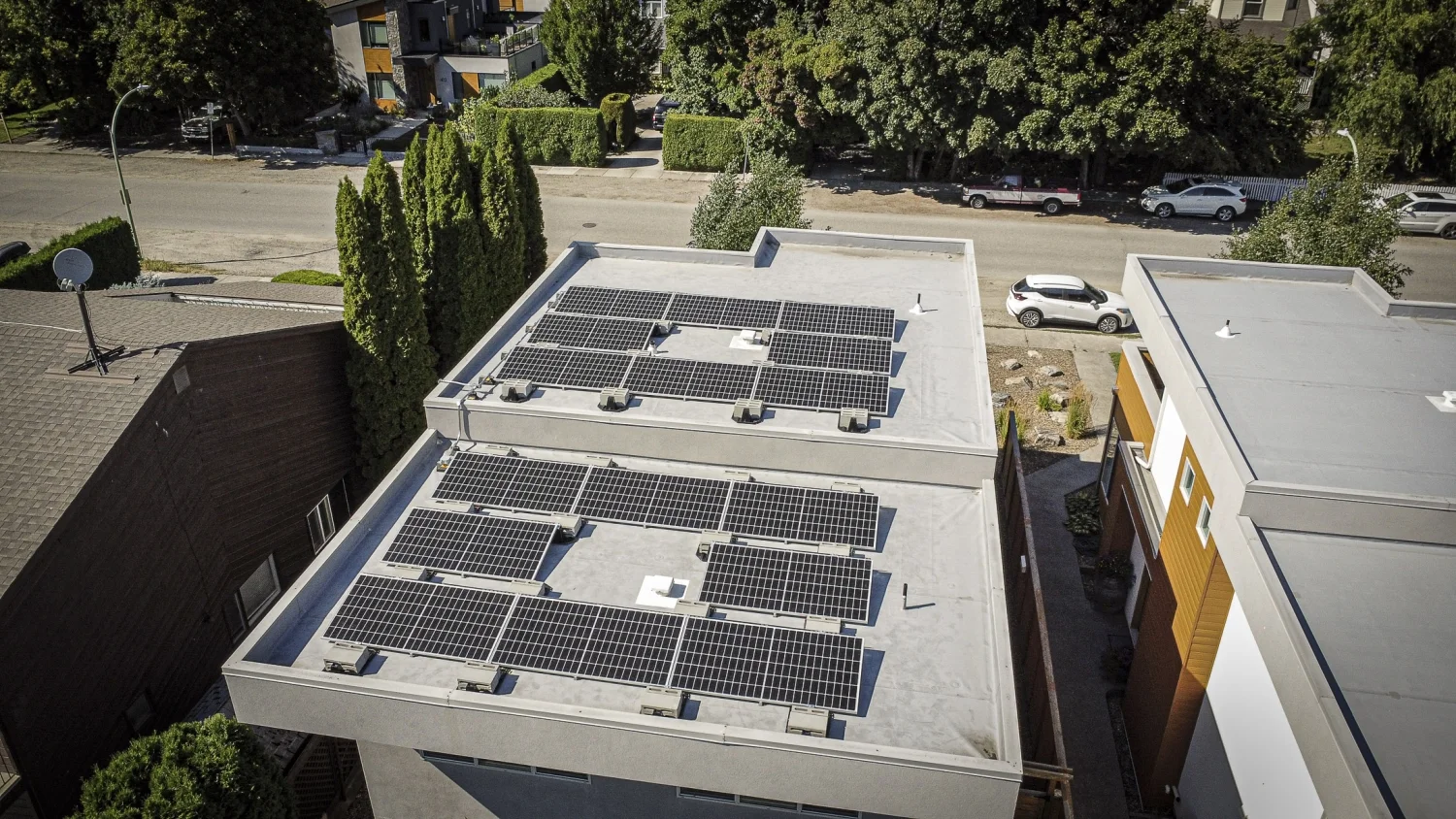 Aerial view of solar panel arrays across two levels of a flat residential roof