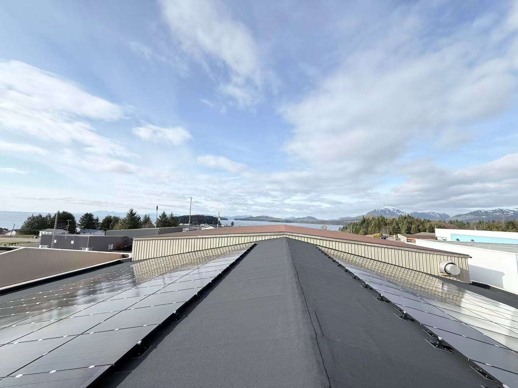 Commercial rooftop solar array overlooking water and mountains